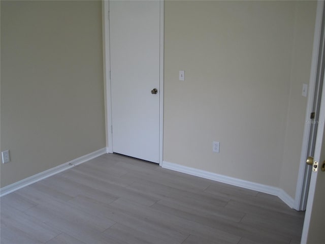 spare room with baseboards and wood finished floors