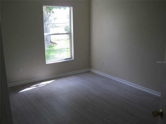 unfurnished room featuring dark wood-style floors and baseboards