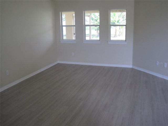 unfurnished room with baseboards and wood finished floors