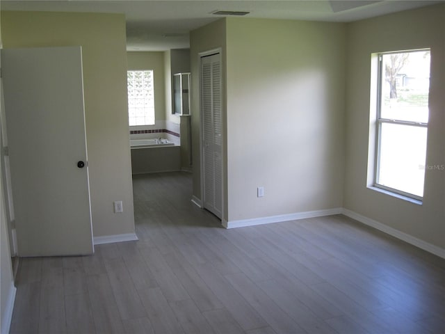 unfurnished room with baseboards, plenty of natural light, visible vents, and wood finished floors