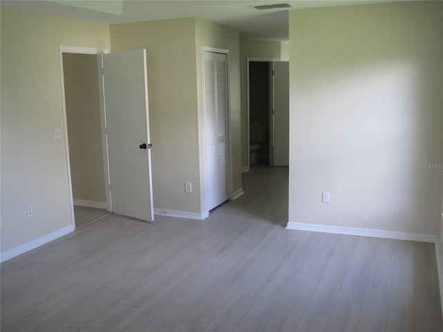 empty room with wood finished floors, visible vents, and baseboards