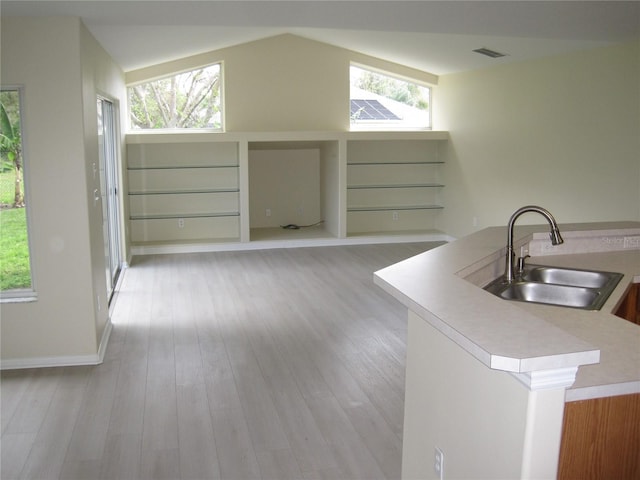 interior space featuring light wood-style floors, lofted ceiling, visible vents, and a sink