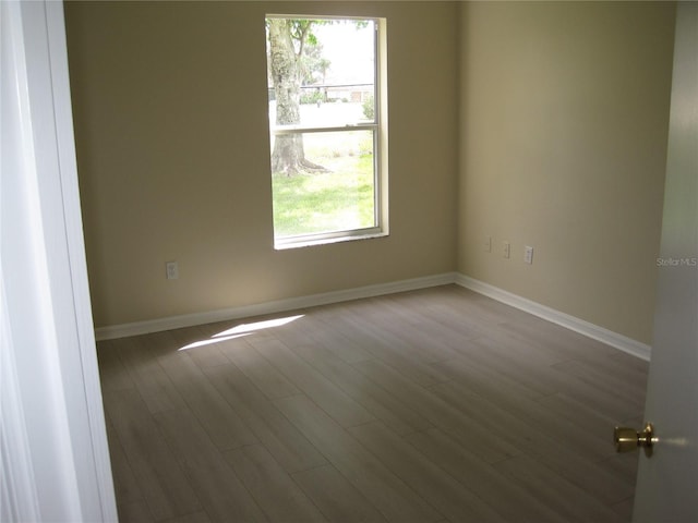 unfurnished room with baseboards and wood finished floors