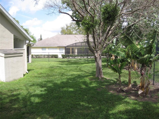 view of yard featuring glass enclosure and fence