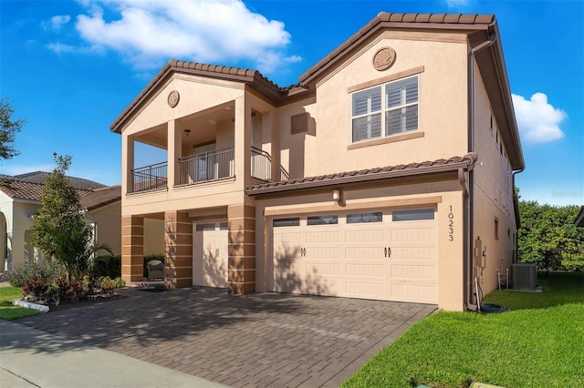 mediterranean / spanish-style home featuring a garage, a balcony, central air condition unit, and a front lawn