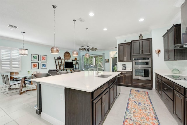 kitchen featuring appliances with stainless steel finishes, pendant lighting, sink, crown molding, and a center island with sink