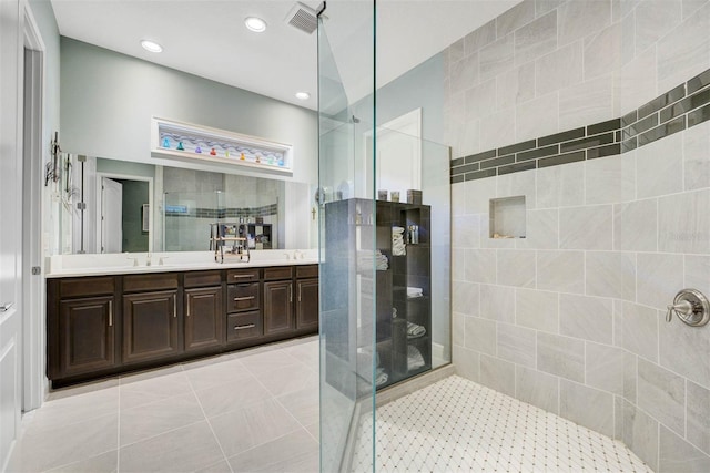 bathroom with tile patterned flooring, vanity, and walk in shower