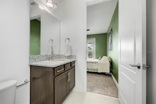 bathroom featuring vanity, a textured ceiling, tile patterned floors, and toilet