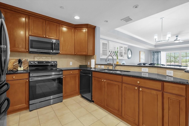 kitchen with sink, light tile patterned floors, dark stone countertops, a tray ceiling, and stainless steel appliances