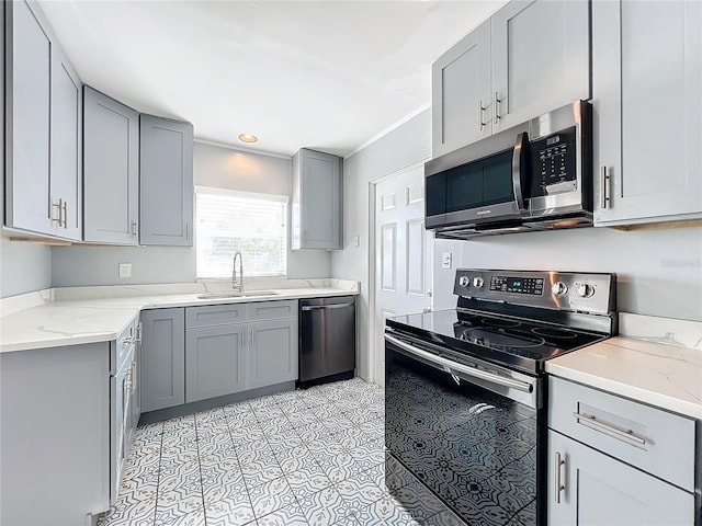 kitchen with gray cabinetry, sink, stainless steel appliances, and light stone countertops