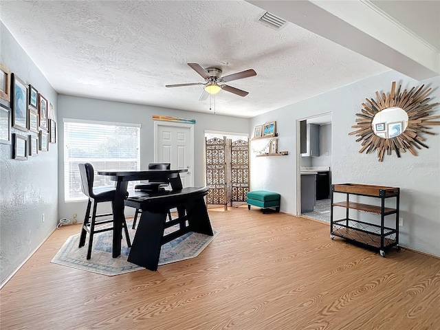 dining area featuring ceiling fan, light hardwood / wood-style floors, and a textured ceiling