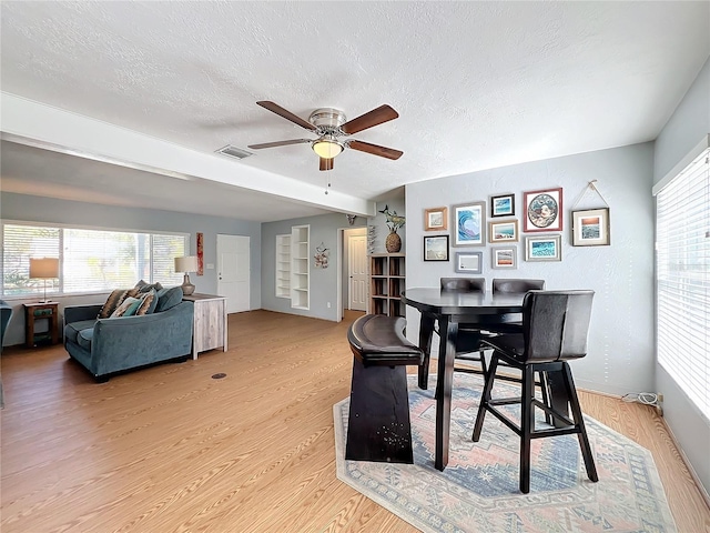 dining space featuring a healthy amount of sunlight, a textured ceiling, and light hardwood / wood-style floors