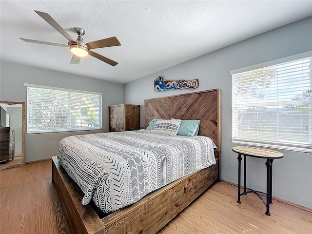 bedroom with ceiling fan, a textured ceiling, and light hardwood / wood-style floors