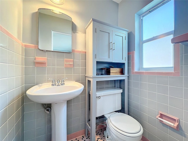 bathroom featuring sink, tile walls, and toilet