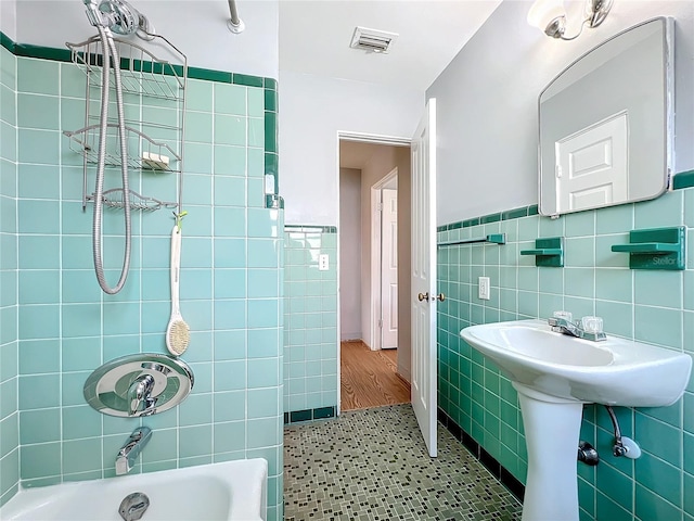 bathroom with a bathing tub, tile walls, and tile patterned floors