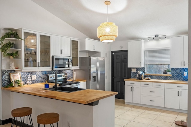 kitchen featuring a breakfast bar, wooden counters, kitchen peninsula, and appliances with stainless steel finishes