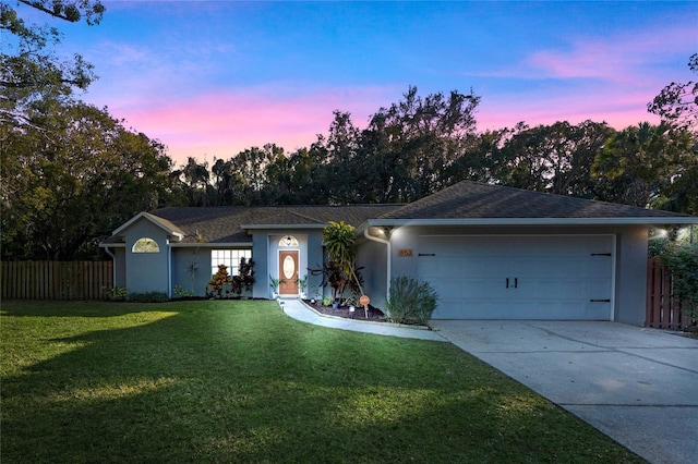 ranch-style house with a garage and a lawn