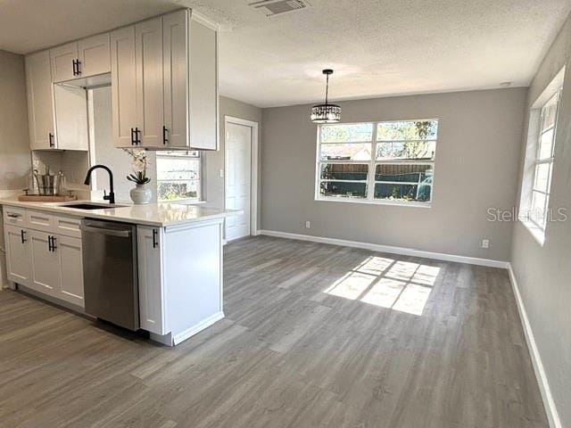 kitchen featuring white cabinetry, a textured ceiling, stainless steel dishwasher, pendant lighting, and hardwood / wood-style floors