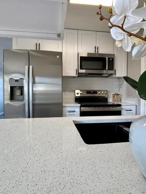 kitchen featuring backsplash, stainless steel appliances, and white cabinets