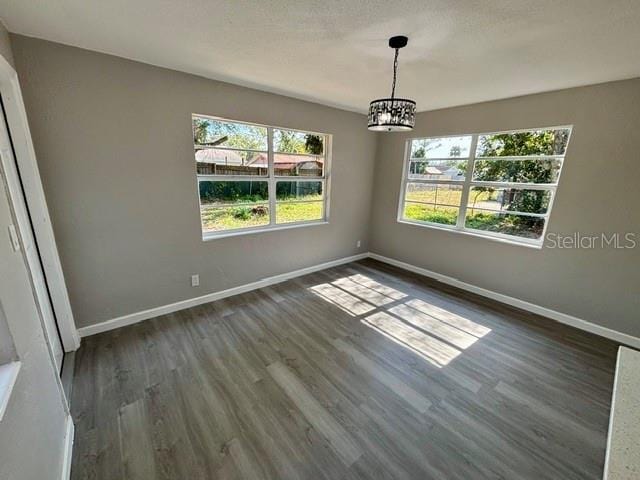 unfurnished dining area featuring dark wood-type flooring and a chandelier