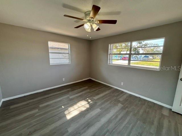 unfurnished room with ceiling fan and dark hardwood / wood-style flooring