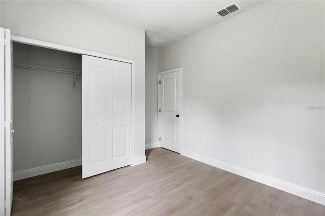 unfurnished bedroom with light wood-type flooring and a closet