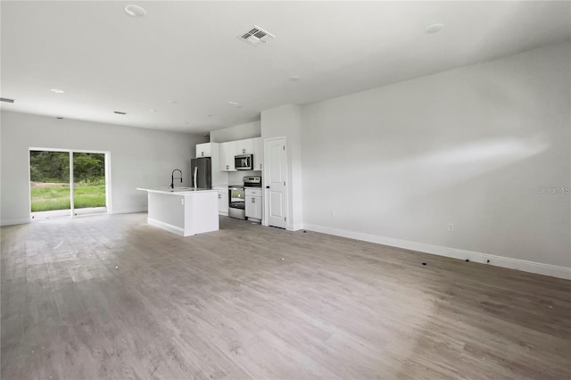 unfurnished living room with sink and light hardwood / wood-style flooring