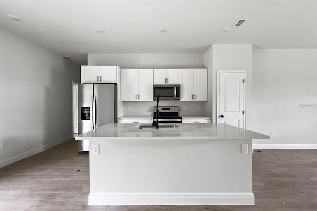 kitchen featuring appliances with stainless steel finishes, an island with sink, sink, white cabinets, and light stone counters