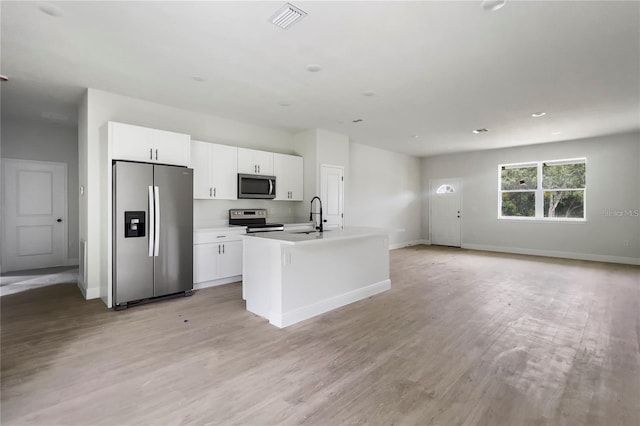 kitchen with sink, appliances with stainless steel finishes, light hardwood / wood-style floors, an island with sink, and white cabinets