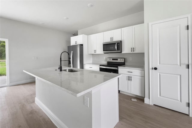 kitchen with hardwood / wood-style floors, an island with sink, white cabinets, and appliances with stainless steel finishes