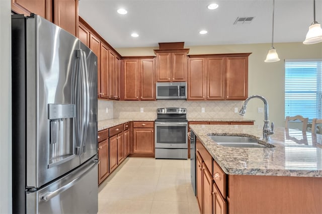 kitchen with sink, appliances with stainless steel finishes, pendant lighting, light stone countertops, and decorative backsplash