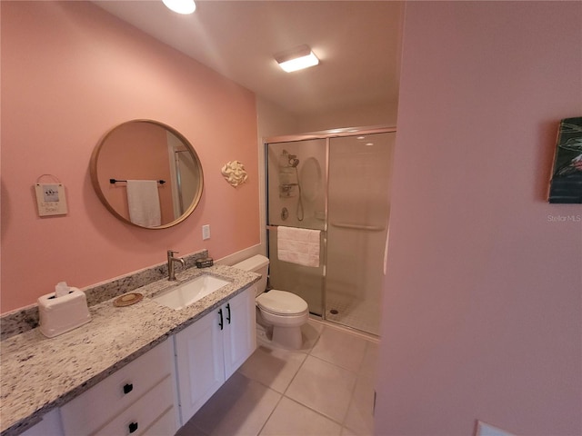 bathroom featuring tile patterned floors, toilet, a shower with door, and vanity