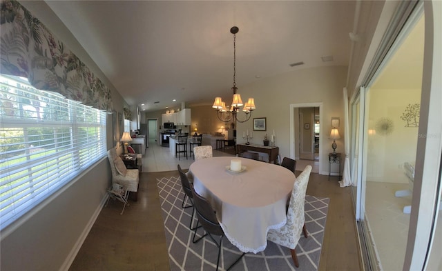 dining area with hardwood / wood-style flooring, lofted ceiling, and a chandelier