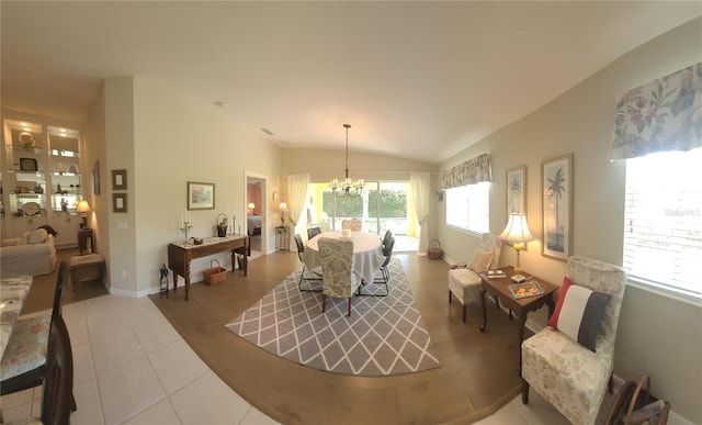 living room with a healthy amount of sunlight, lofted ceiling, a chandelier, and tile patterned flooring