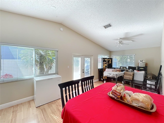 dining room featuring french doors, vaulted ceiling, light hardwood / wood-style floors, and a wealth of natural light