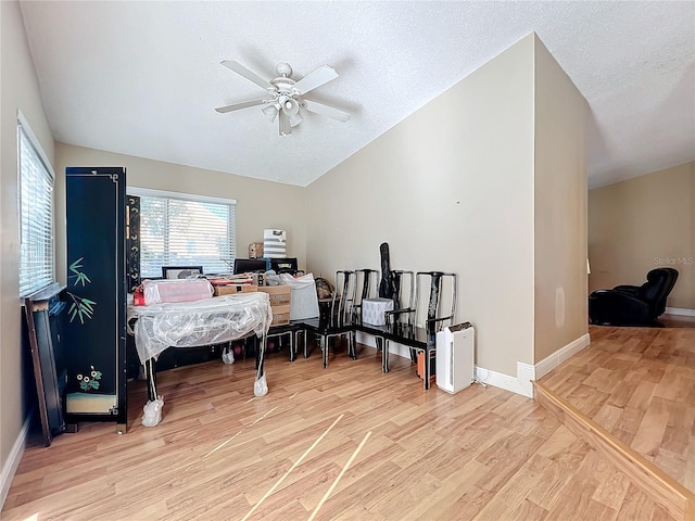 bedroom with ceiling fan, lofted ceiling, a textured ceiling, and light hardwood / wood-style floors