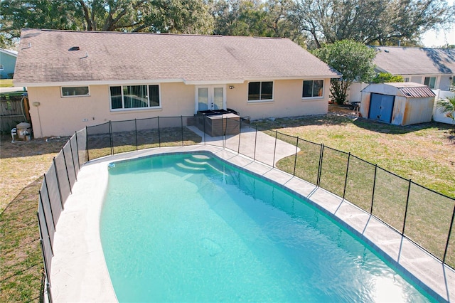 view of swimming pool with a storage shed, a yard, and french doors