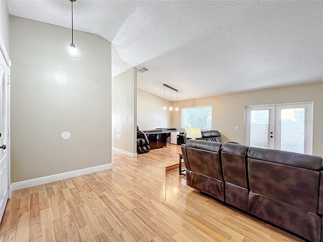 living room featuring french doors, lofted ceiling, light hardwood / wood-style floors, and a textured ceiling