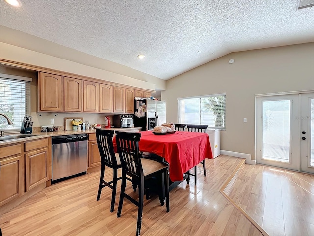 kitchen featuring lofted ceiling, sink, stainless steel appliances, plenty of natural light, and light wood-type flooring