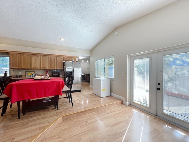 kitchen with light hardwood / wood-style flooring, stainless steel fridge, french doors, and a healthy amount of sunlight