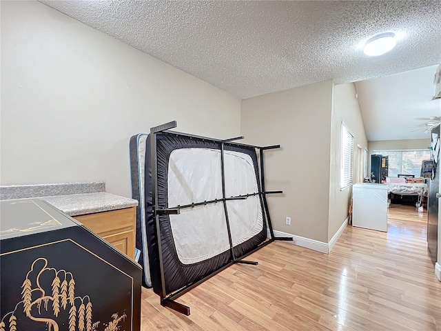 bedroom with lofted ceiling, a textured ceiling, and light wood-type flooring