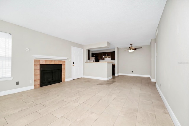 unfurnished living room with a tile fireplace and ceiling fan