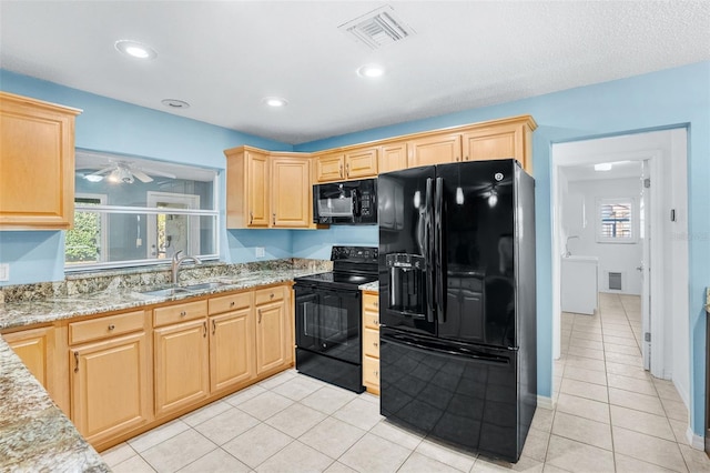 kitchen with plenty of natural light, sink, light stone counters, and black appliances