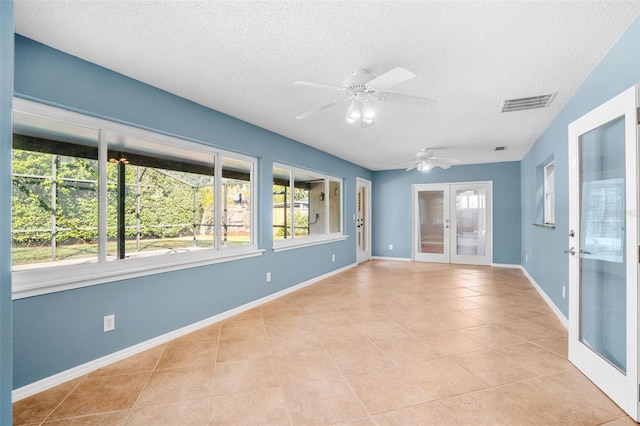 tiled empty room with french doors, ceiling fan, and a textured ceiling