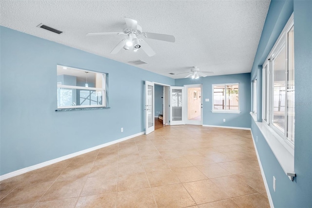 empty room featuring light tile patterned floors, a textured ceiling, and ceiling fan