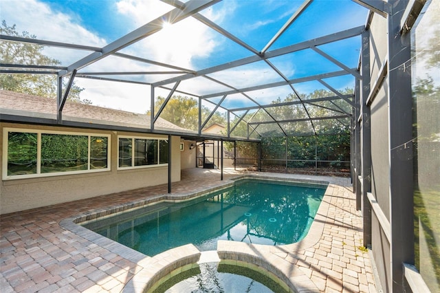 view of pool with a patio area, an in ground hot tub, and glass enclosure