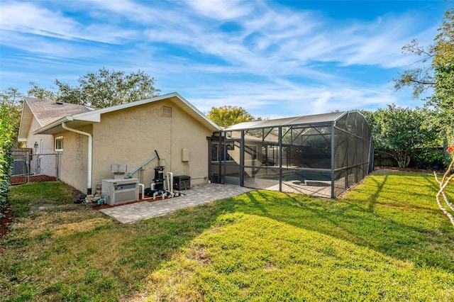 back of property featuring a patio area, a lawn, and glass enclosure