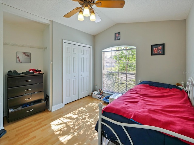 bedroom featuring lofted ceiling, ceiling fan, hardwood / wood-style floors, a textured ceiling, and a closet