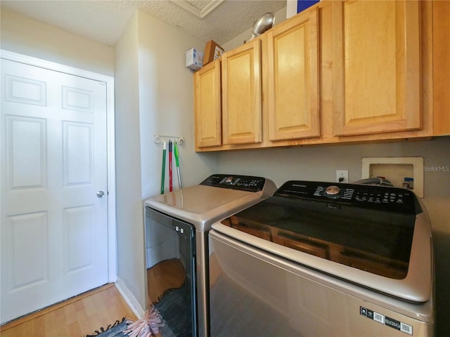 washroom featuring hardwood / wood-style floors, washer and clothes dryer, cabinets, and a textured ceiling