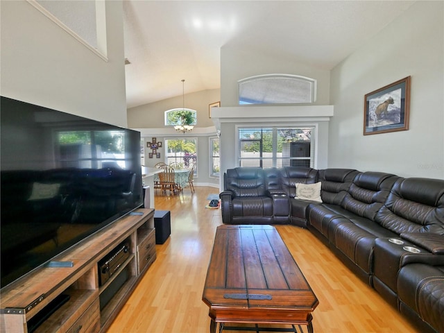 living room with high vaulted ceiling, an inviting chandelier, and light hardwood / wood-style floors